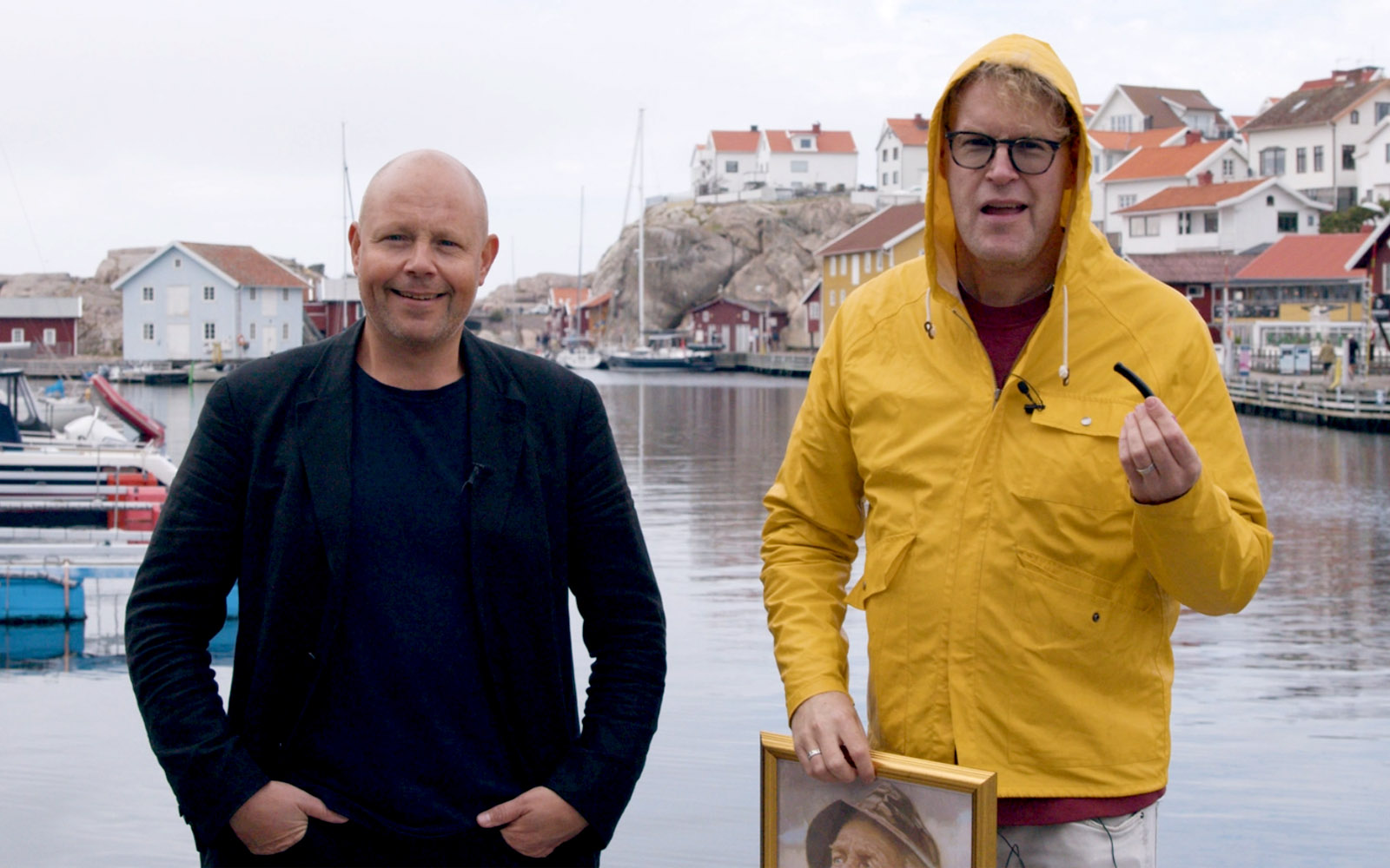 Johan och Lennart står på en brygga i Kungshamn med vattnet i bakgrunden. Lennart håller i en lakritspipa.